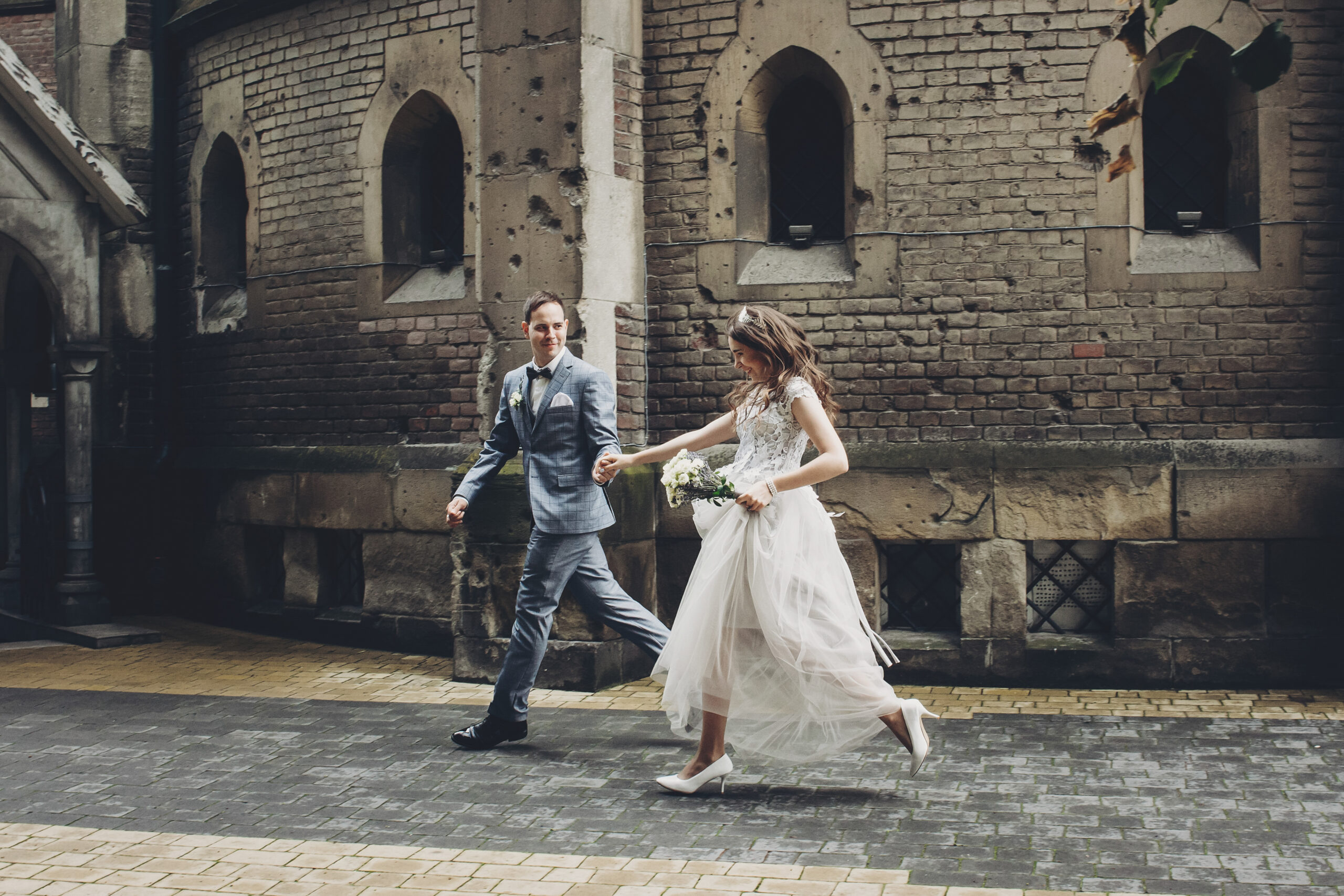 Beautiful emotional wedding couple running and smiling in europe
